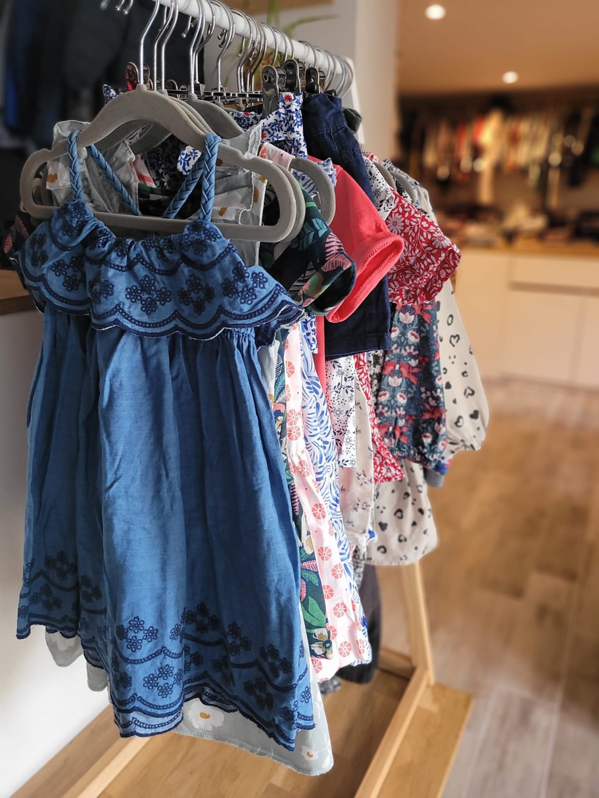 Sarah dans la boutique, devant les portants